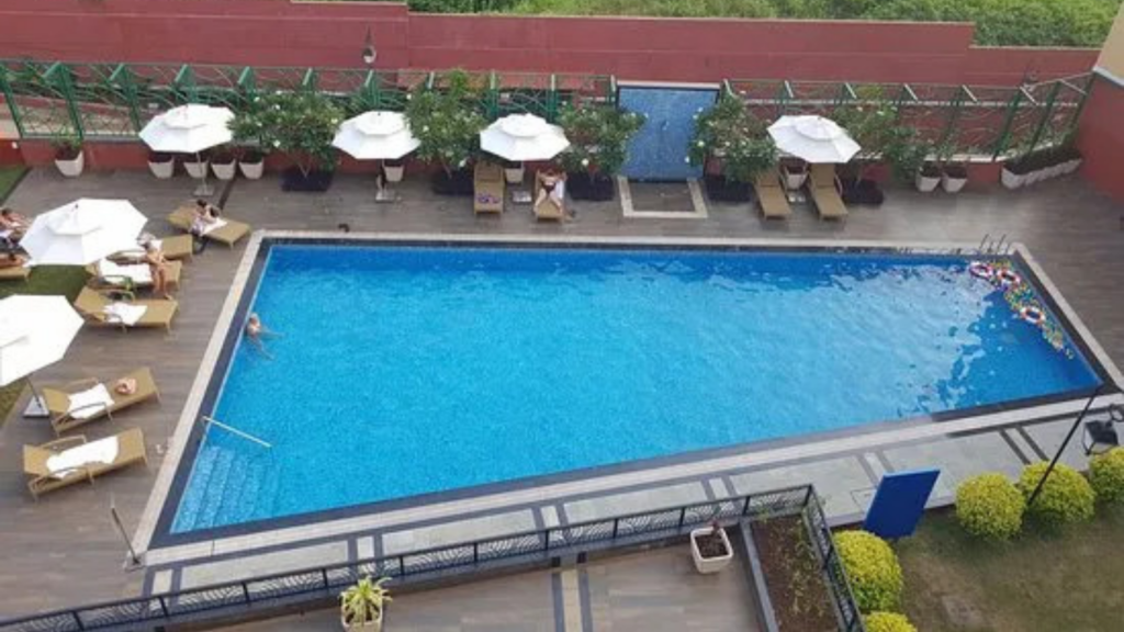 Hotel balcony view overlooking swimming pool and lush greenery in Goa